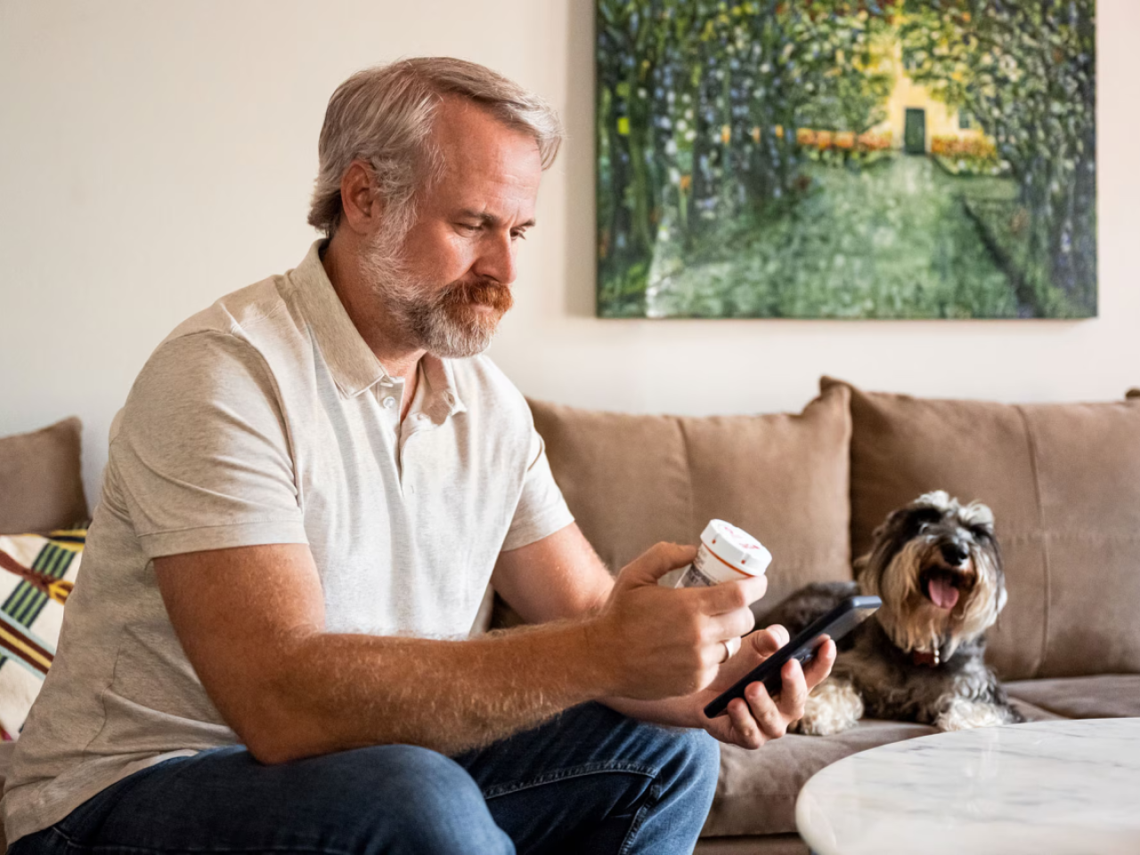 Man looking at medicine bottle while picking up the phone