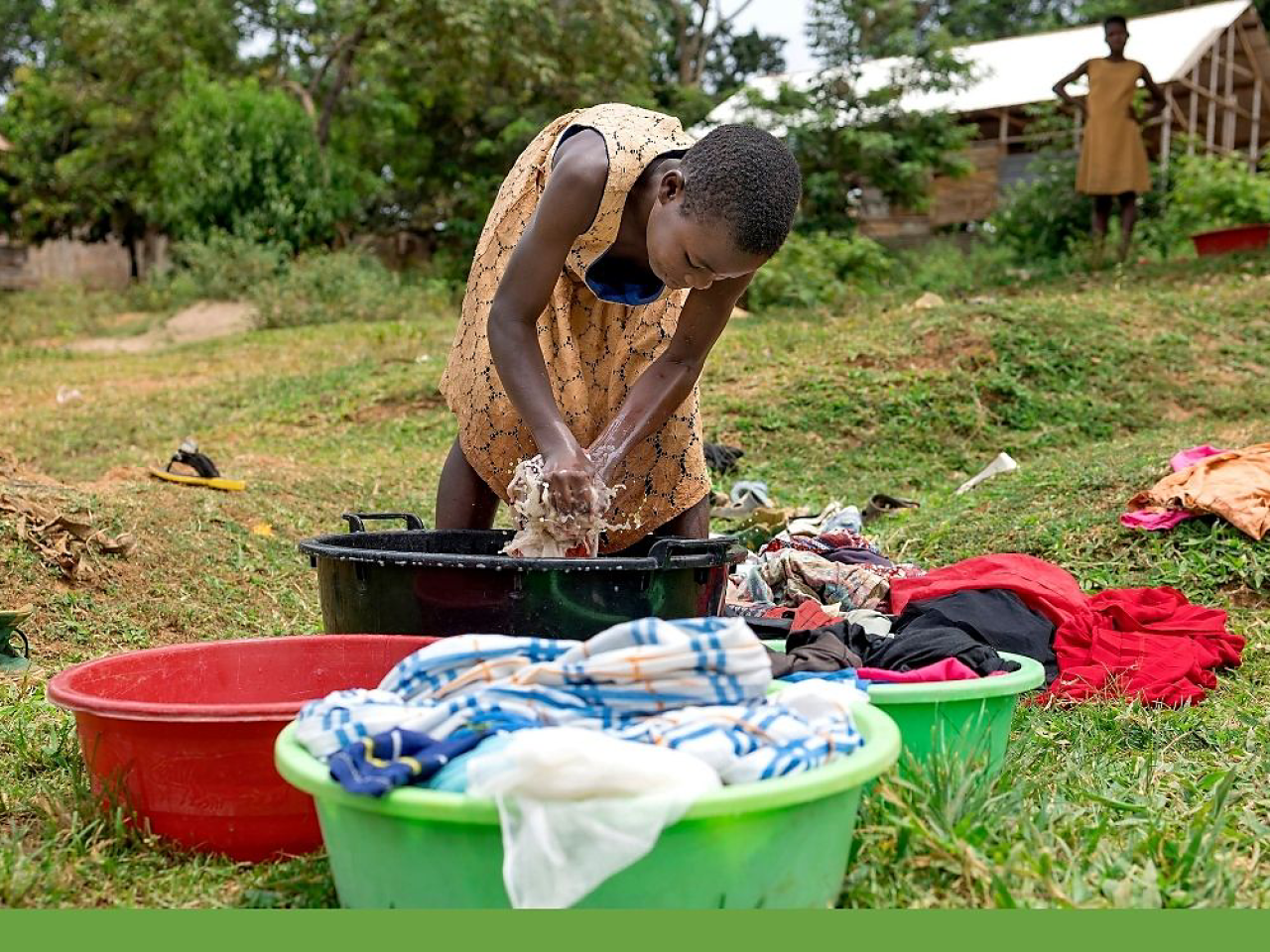 Girl hand washing clothes out of doors