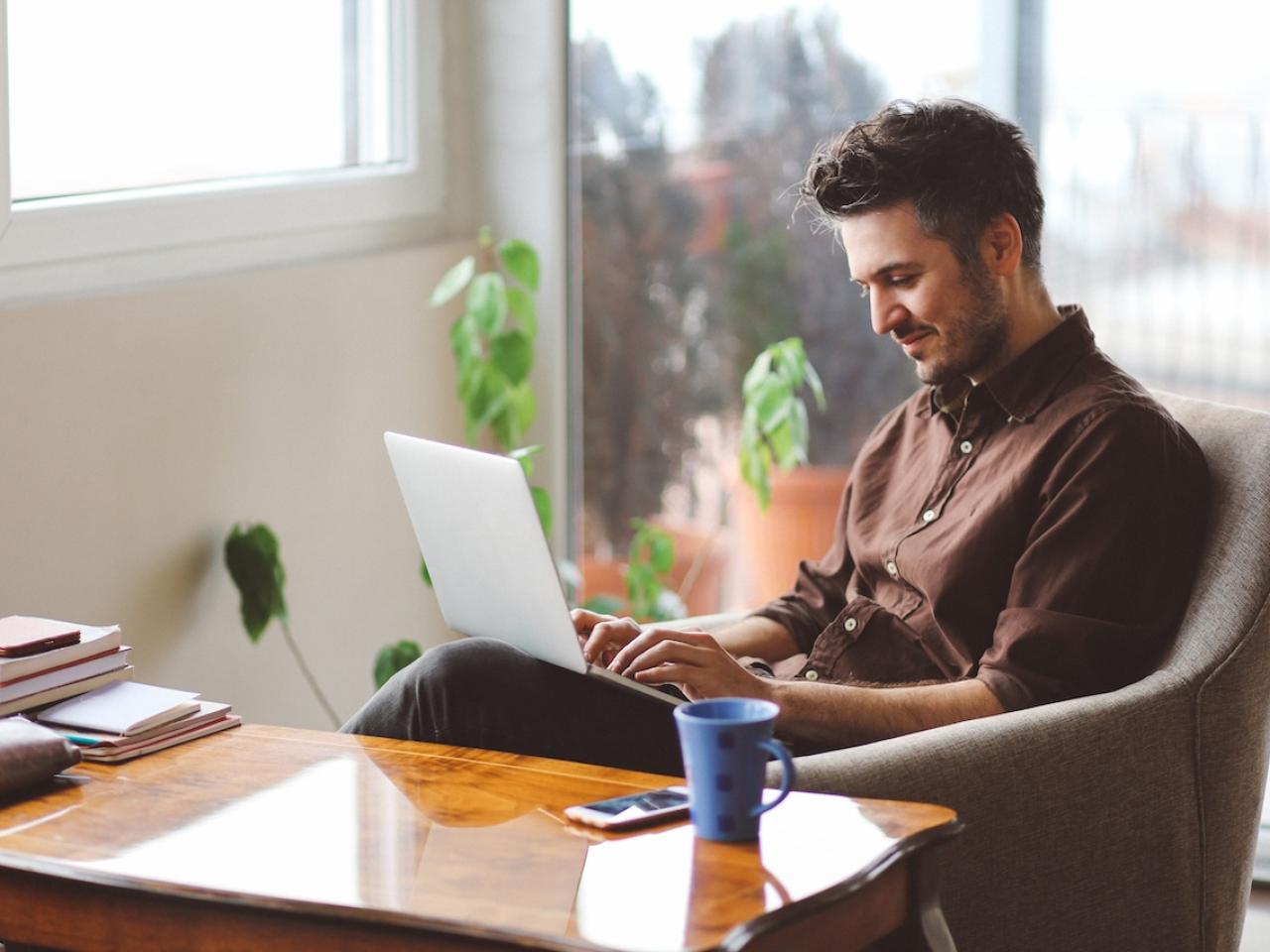 A person seated at a desk working on a laptop.