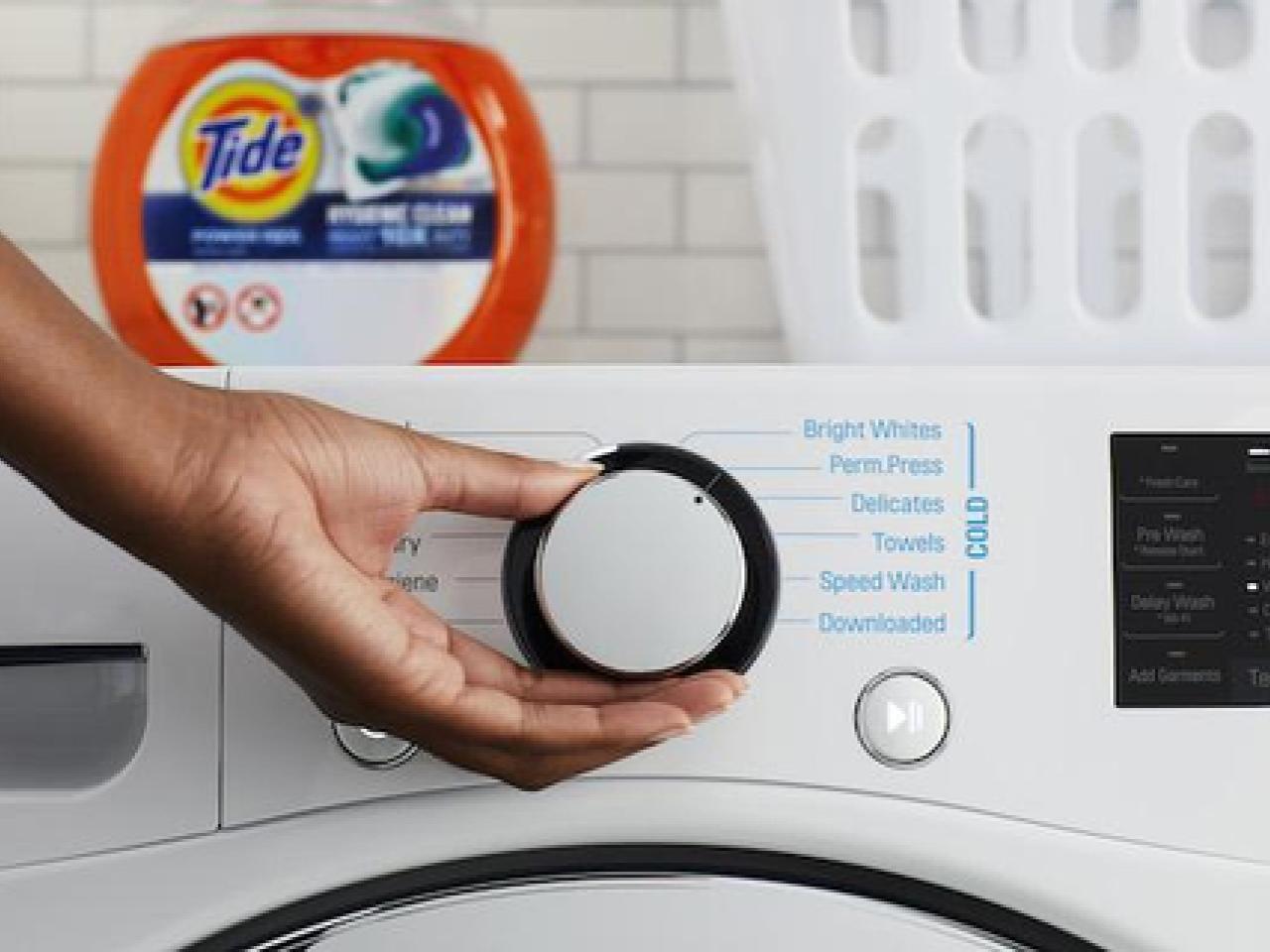 Person turning the dial on a washing machine 