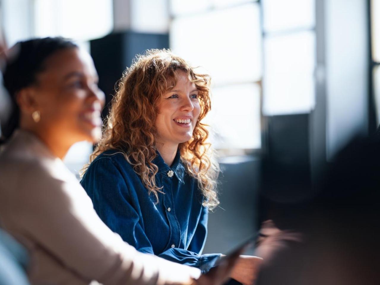 Smiling Colleagues Engaging During an Informal Office Meeting in Brightly Lit Space