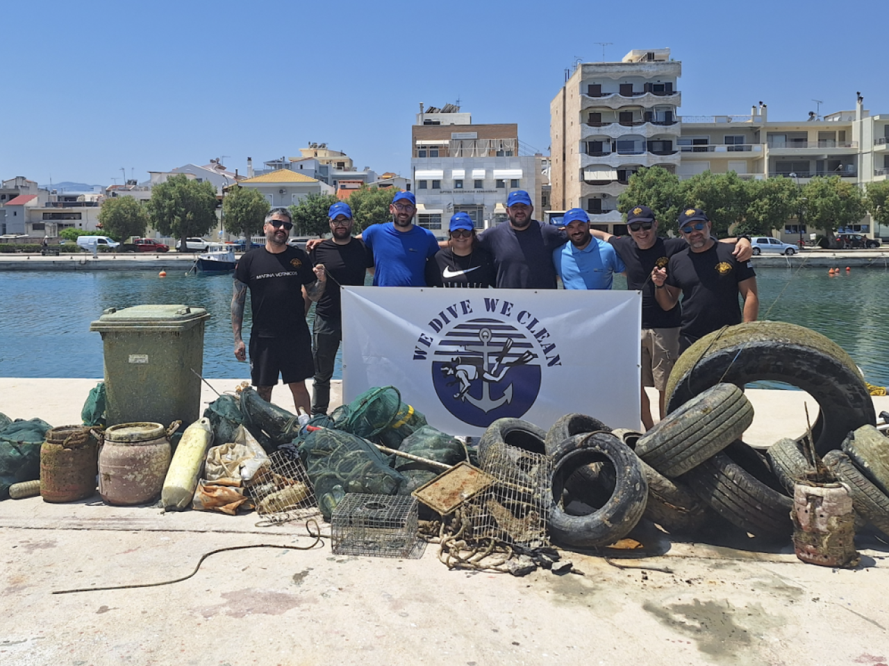Group photo of volunteers next to the large pile of garbage they removed from the water