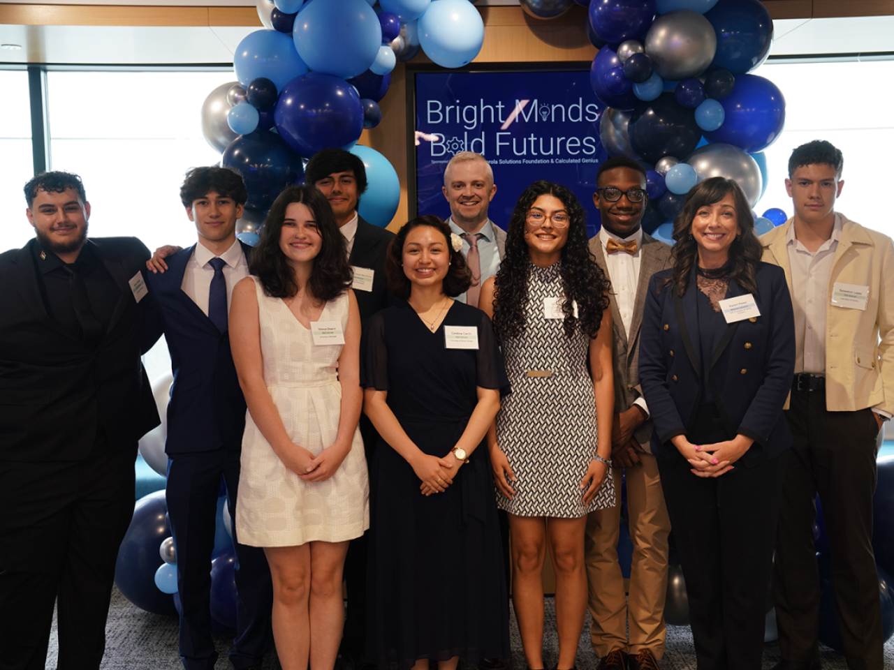 People smiling and standing together under blue balloons
