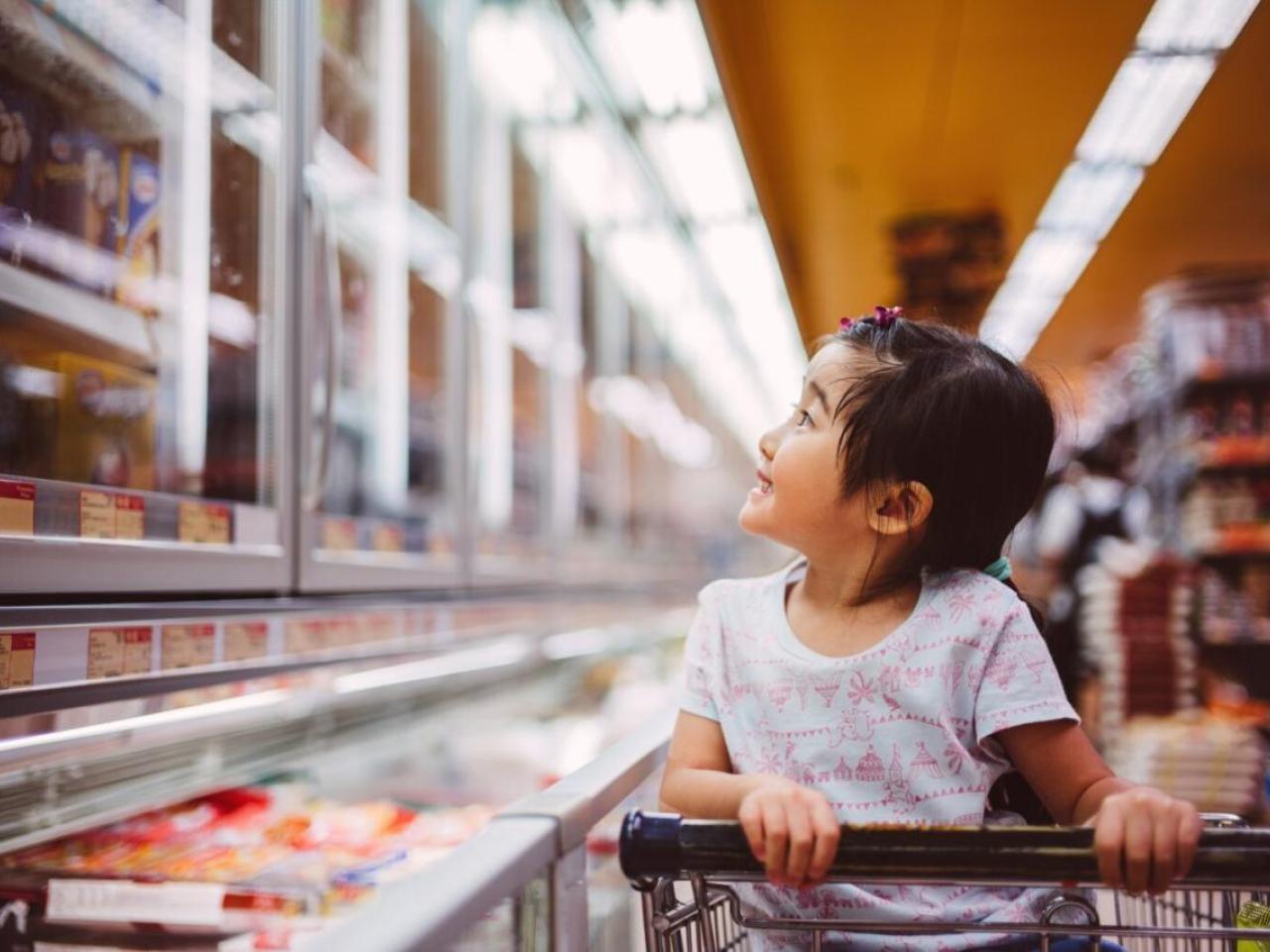 A child seated in a shopping at looking at items