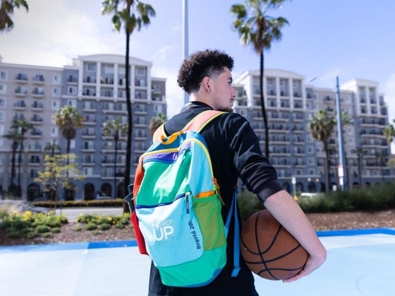 Person with a colorful "Project UP" backpack holding a basketball