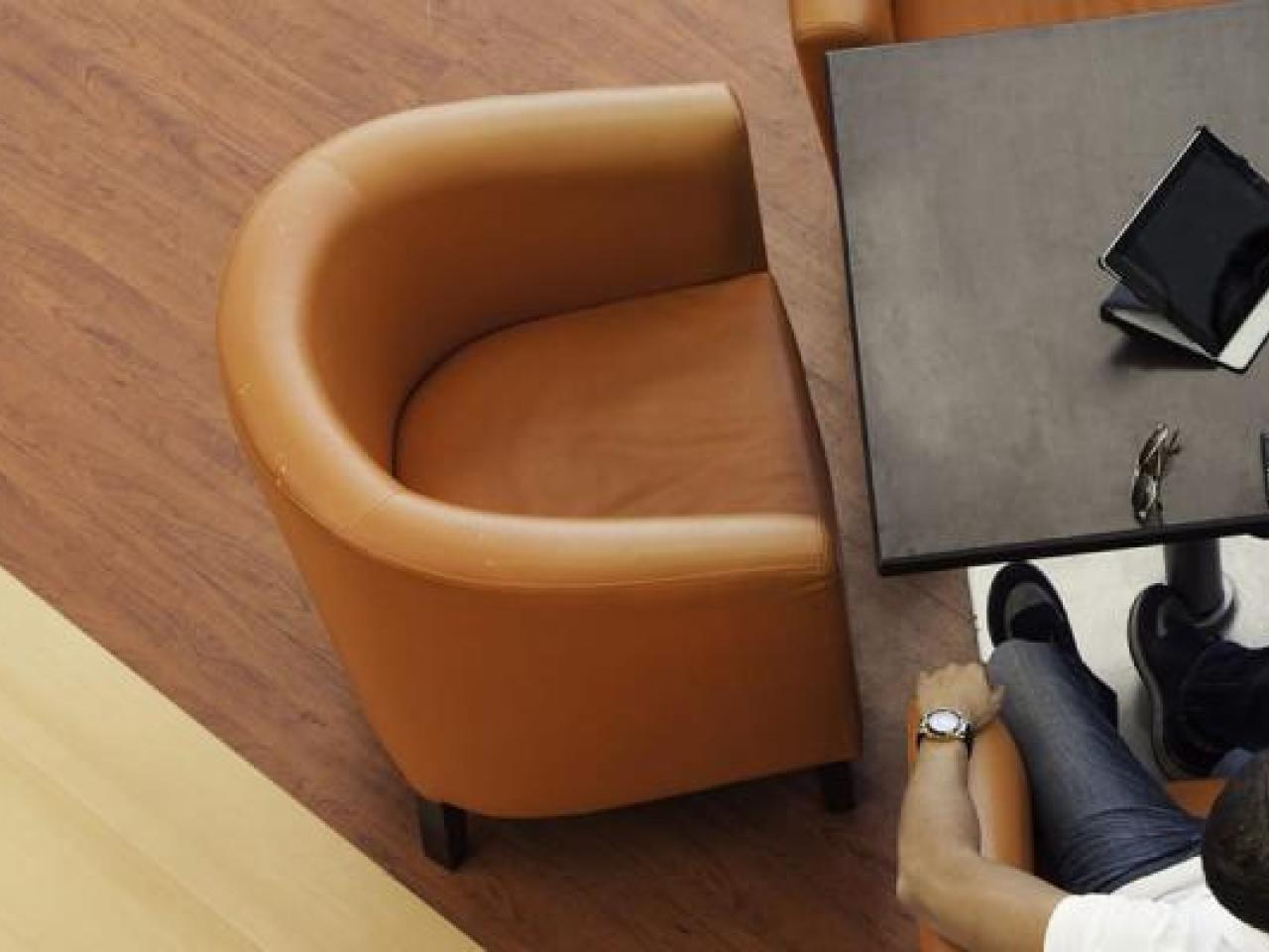Two people seated in armchairs, a laptop open on a small table in front of them.