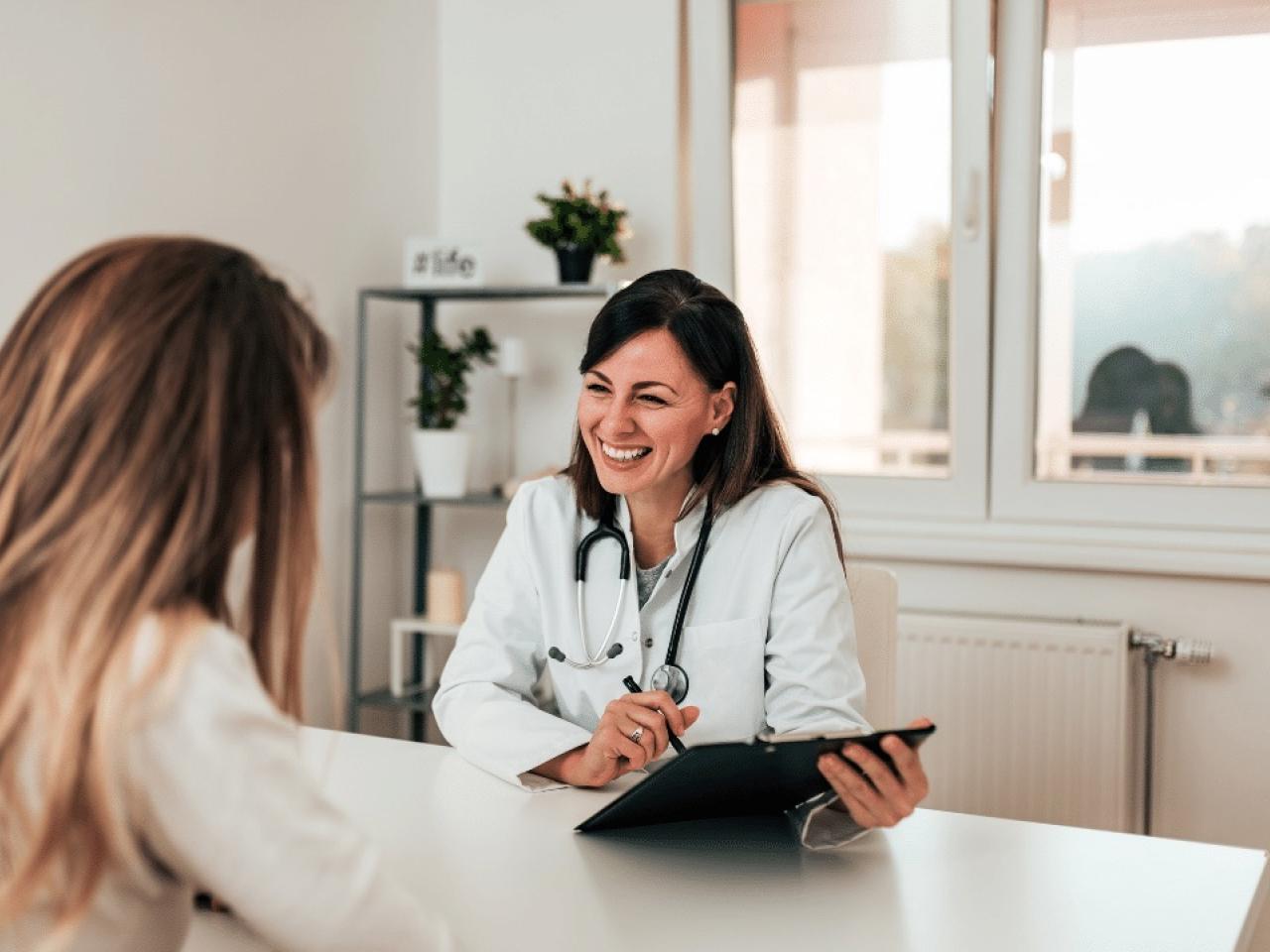 doctor sitting across a table from a patient in a medical office