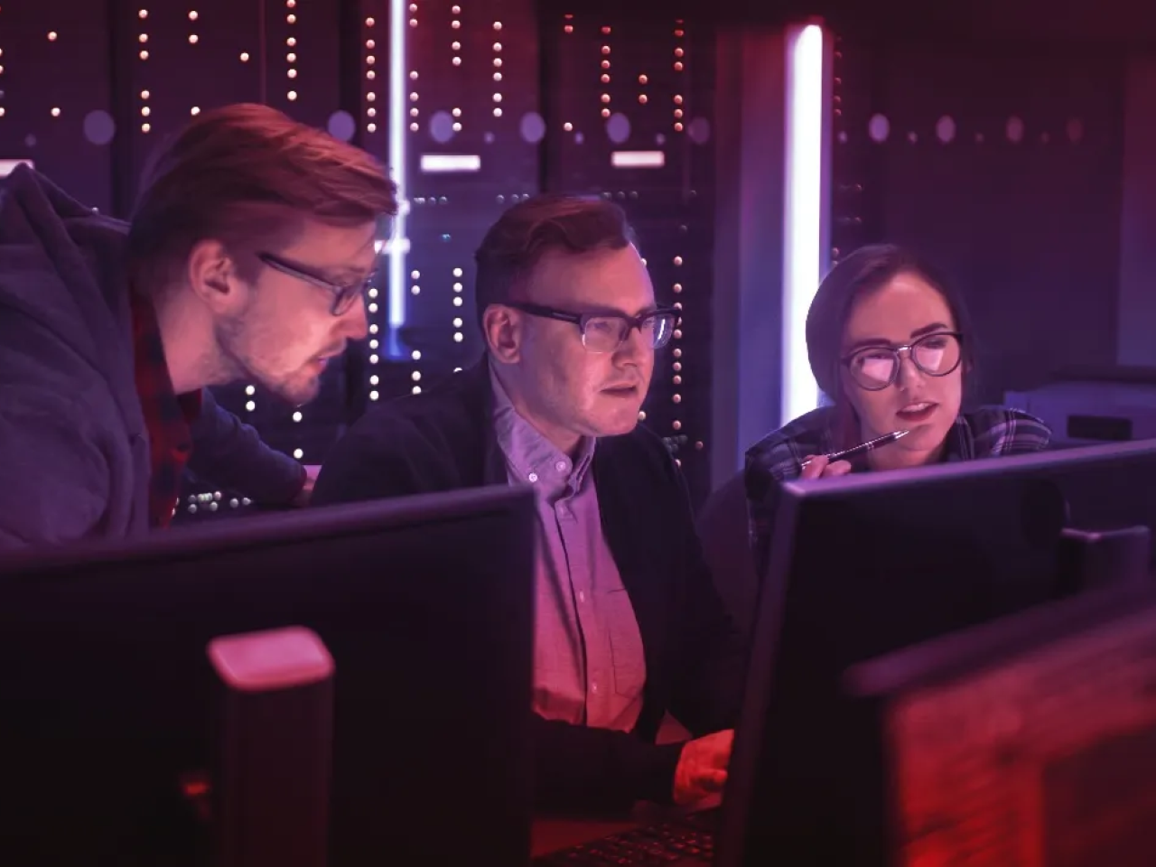 Three people looking at computer monitors