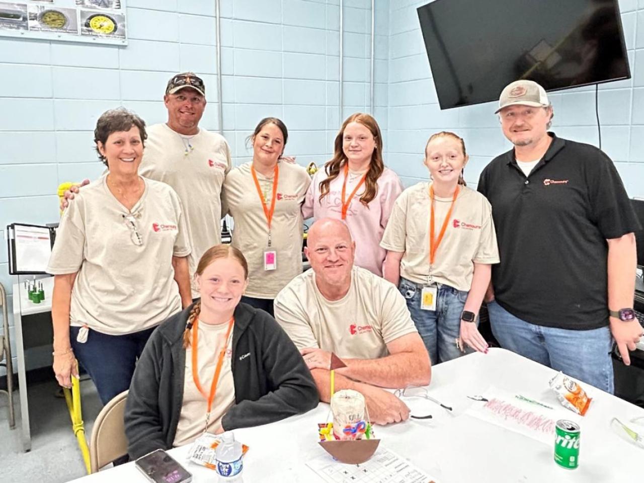 A group of 8 people posing in a cafeteria