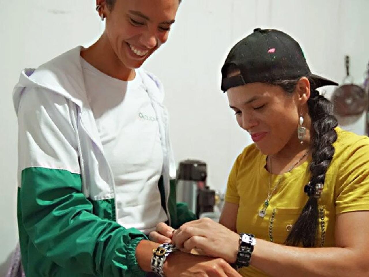 Woman assisting customer in trying on bracelet