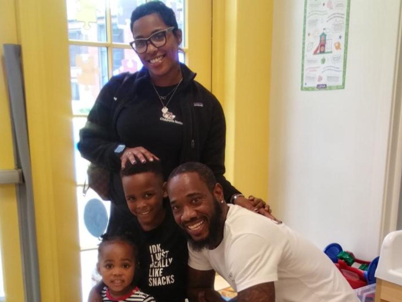 A smiling family posed in a classroom.