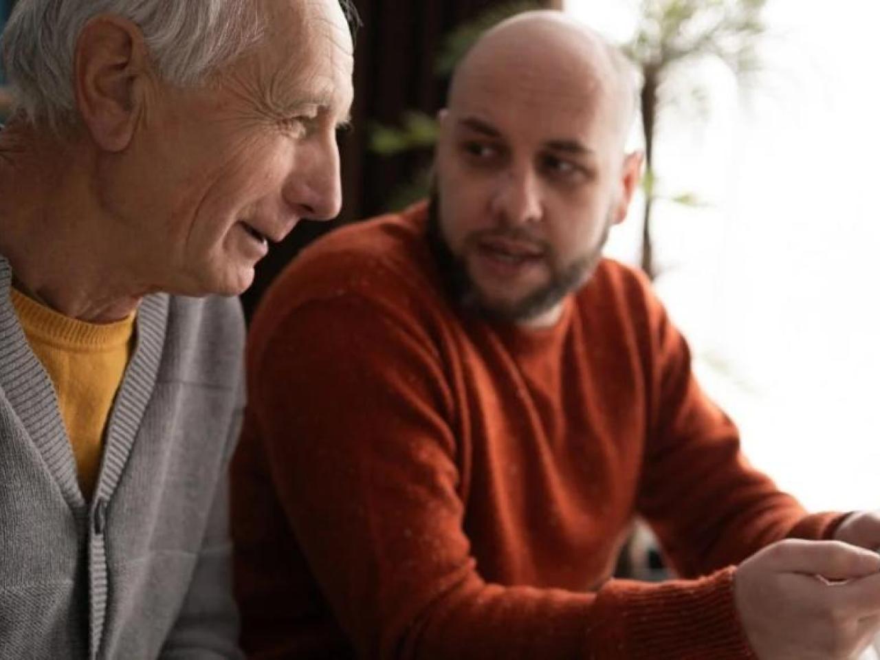 Senior speaking to a younger man about a smartphone