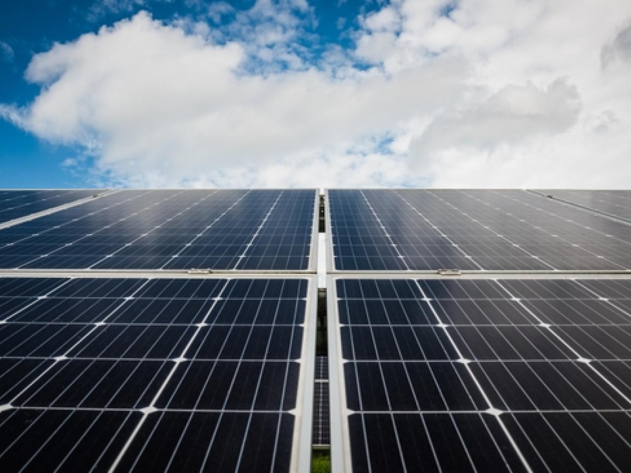 Solar panels against blue sky with clouds