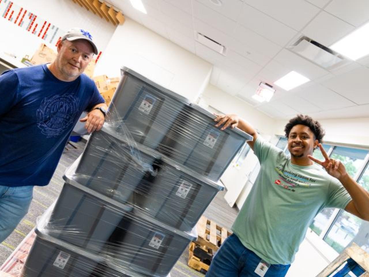 Two volunteers next to large boxes
