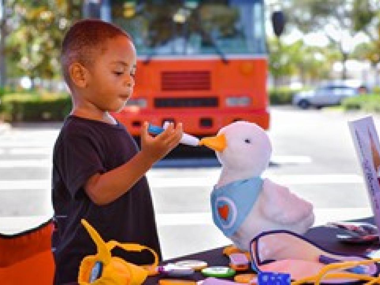 Gabe using a toy syringe to feed his Aflac stuffed duck