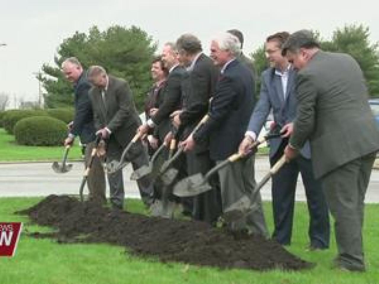 Group of people in suits using shovels to dig up some dirt