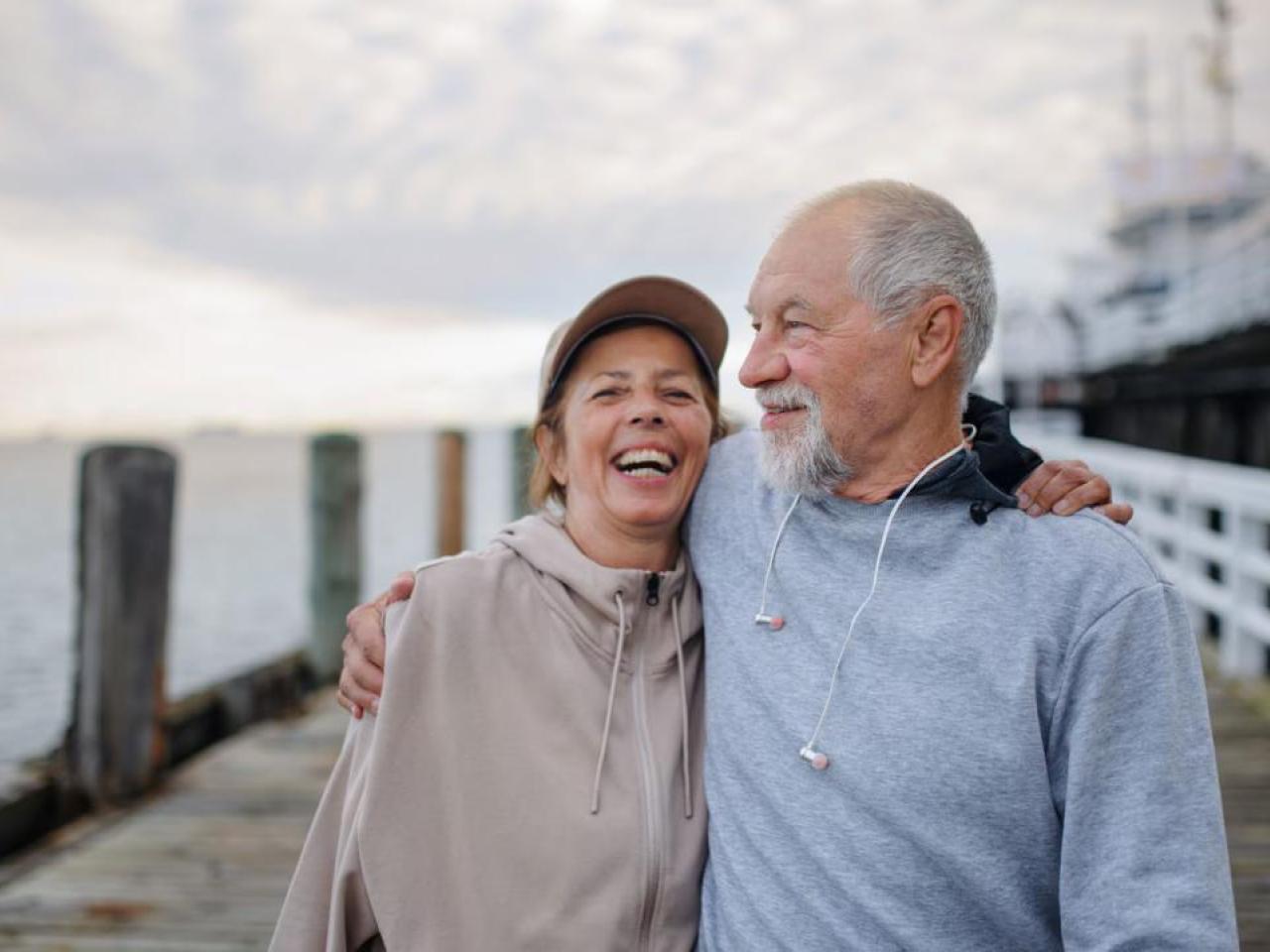 A man and woman shown on a pier in an embrace.