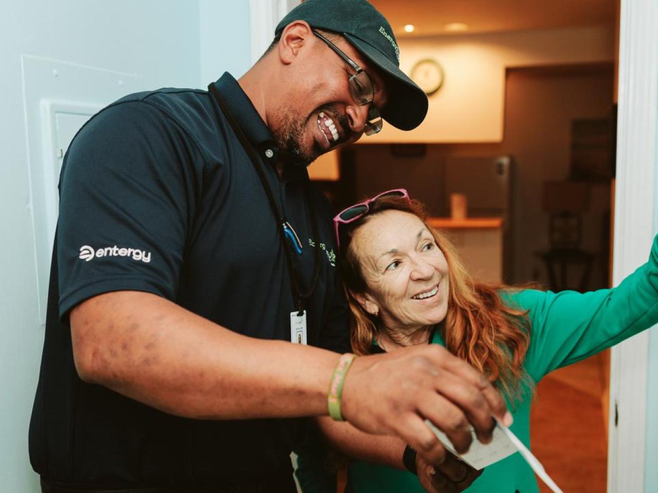 An Entergy employee helping a customer adjust a thermostat