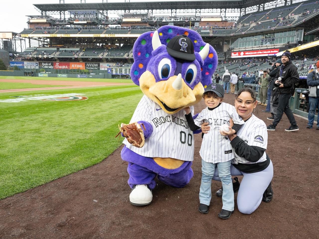 Colorado Rockies mascot with a child and adult on a baseball field