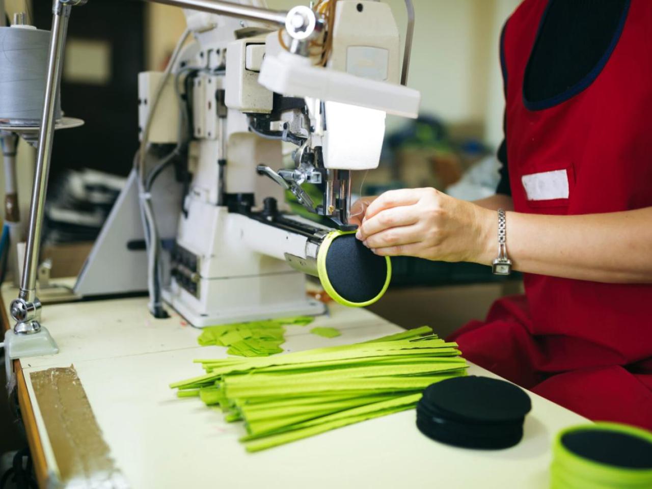 Worker in a factory sewing on a zipper