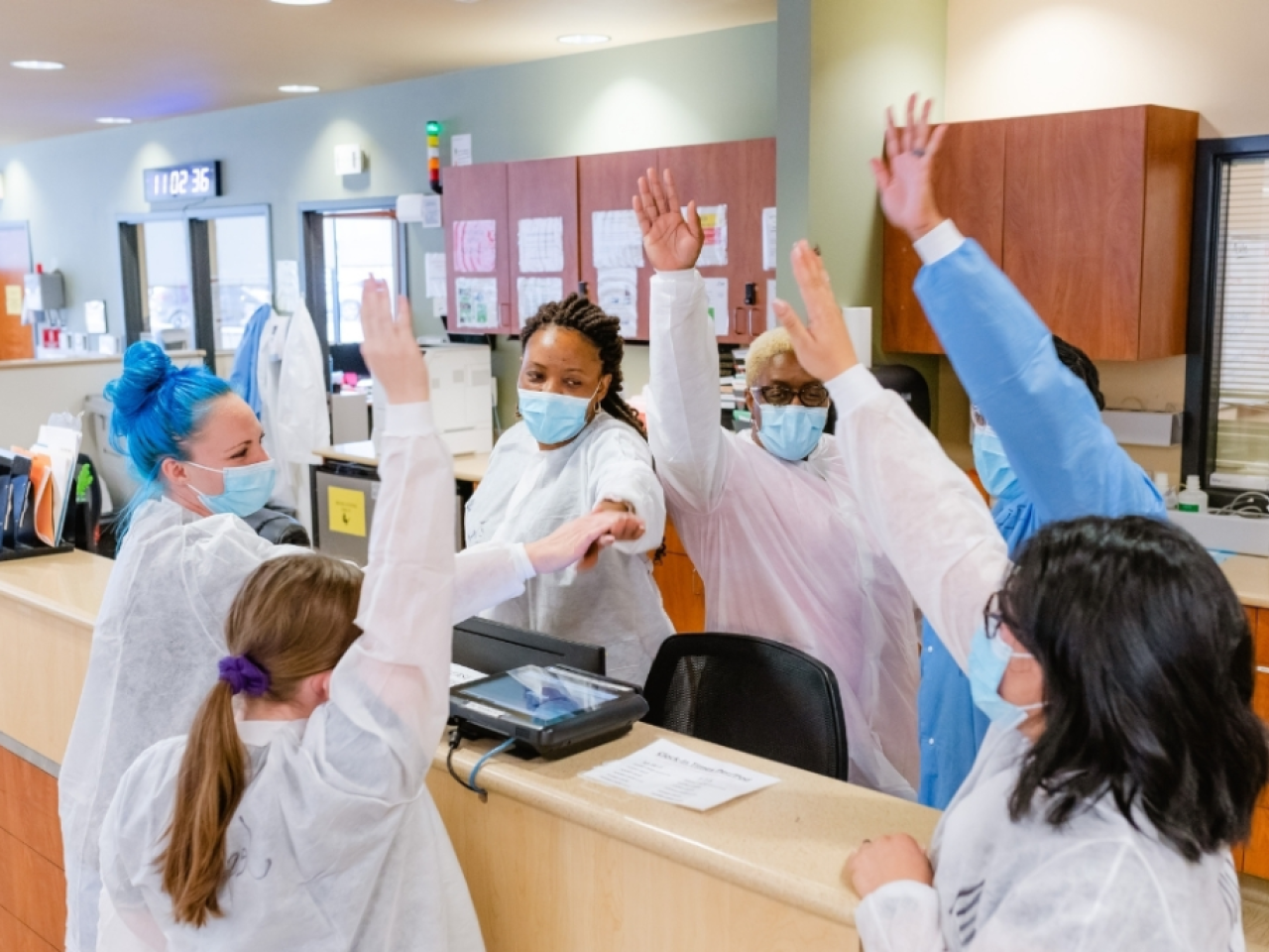 nurses raising their hands at a nursing station