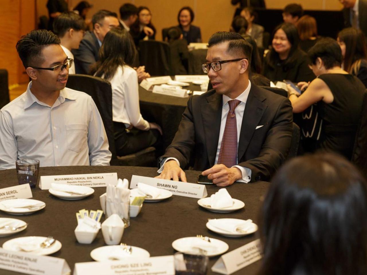 People sitting together and talking at a round dinner event table
