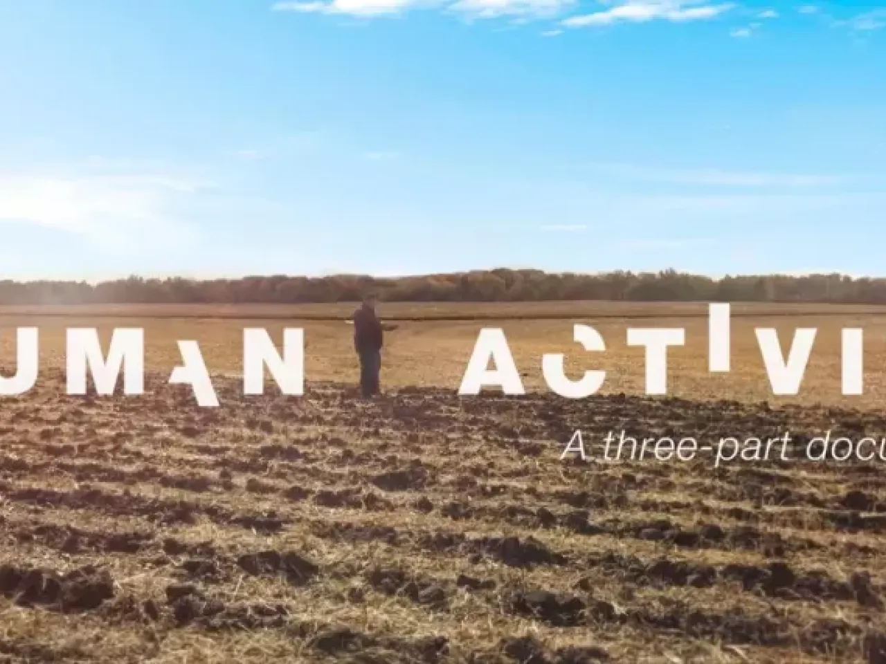 In white broken letters "Human activity". A person standing in a bare crop field, a blue sky above.
