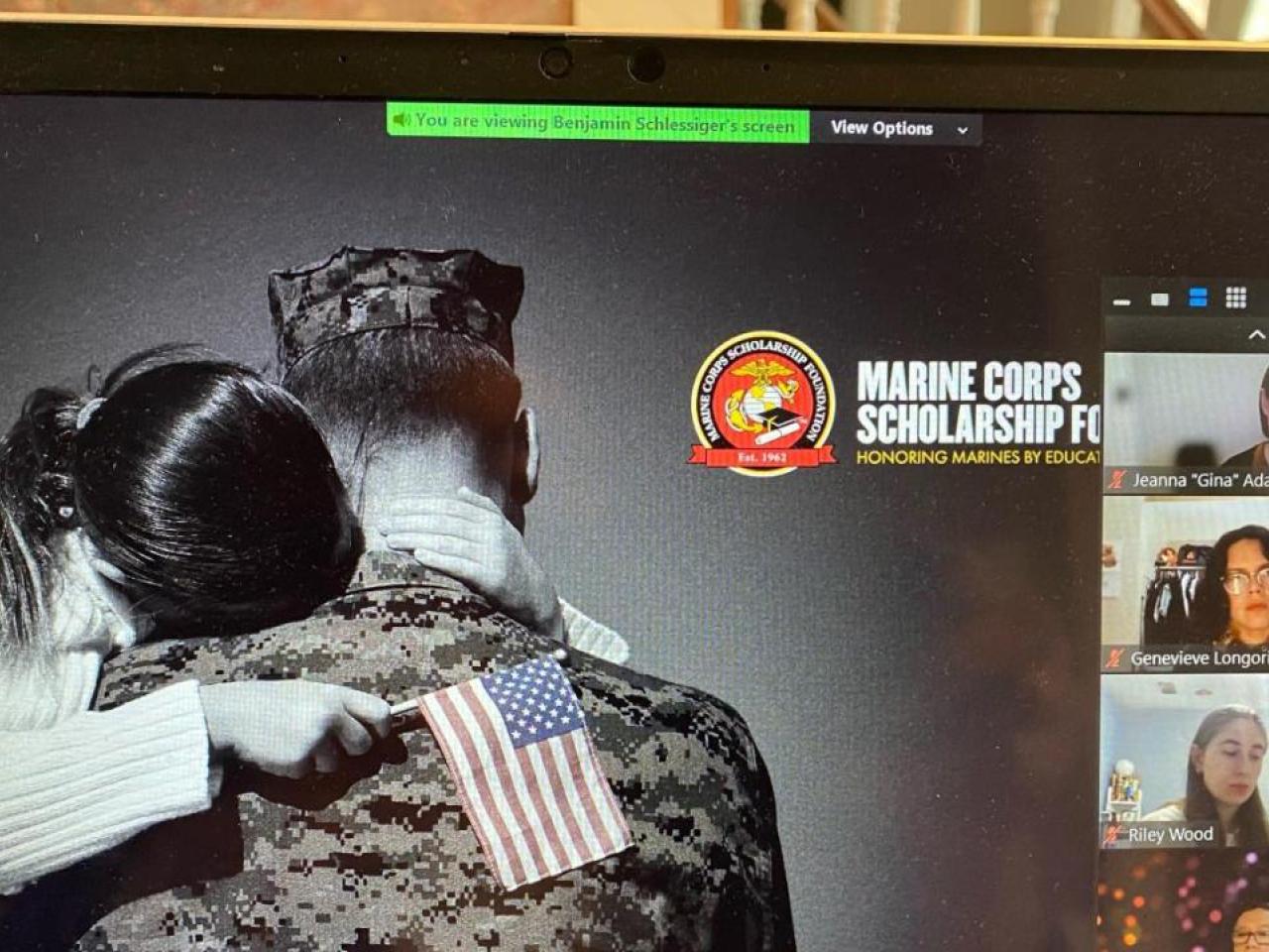 A laptop screen displaying a veteran hugging a child who is holding the American flag