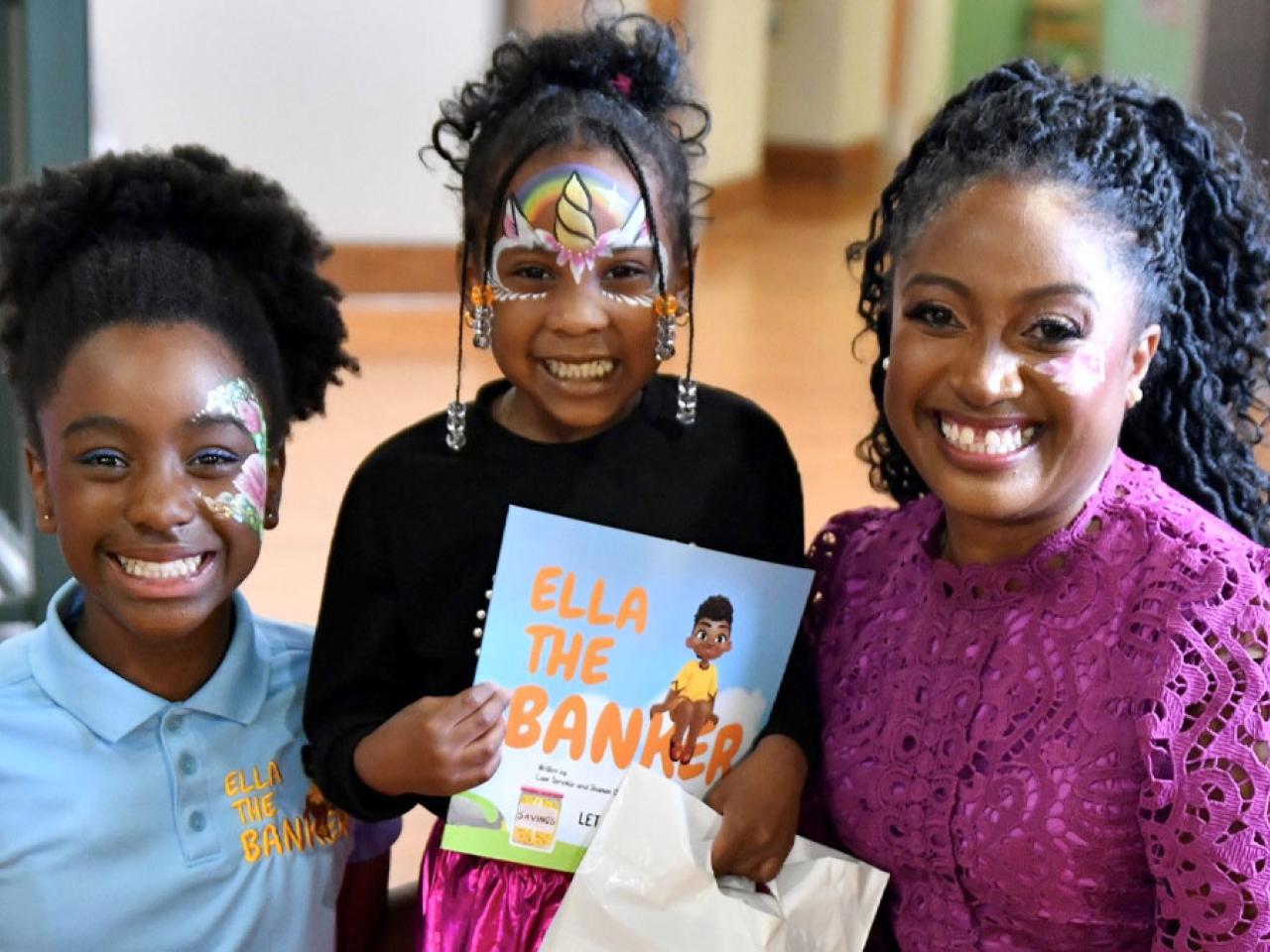 Shamim Okolloh, right, and her daughter, Ella, left, are joined by a young reader holding the book inspired by Ella and written by Ella's brother, Liam.