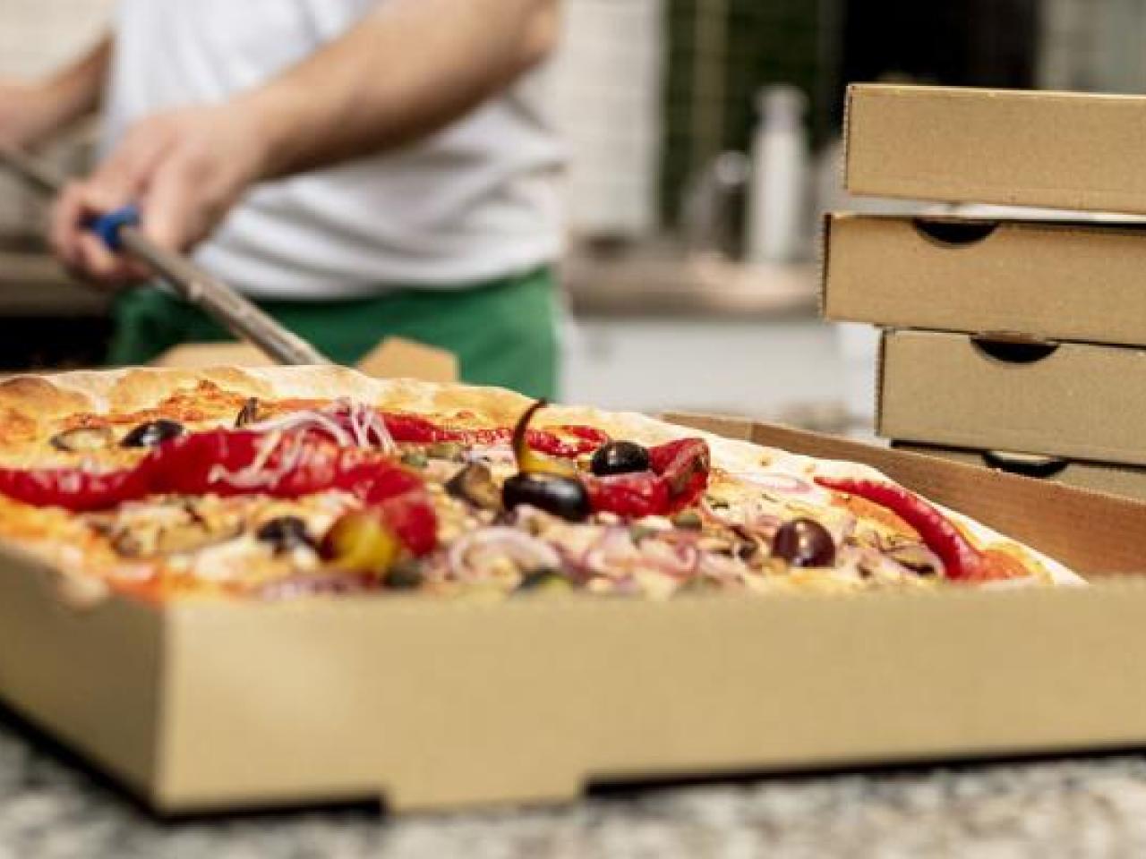 A person placing a pizza in a box.