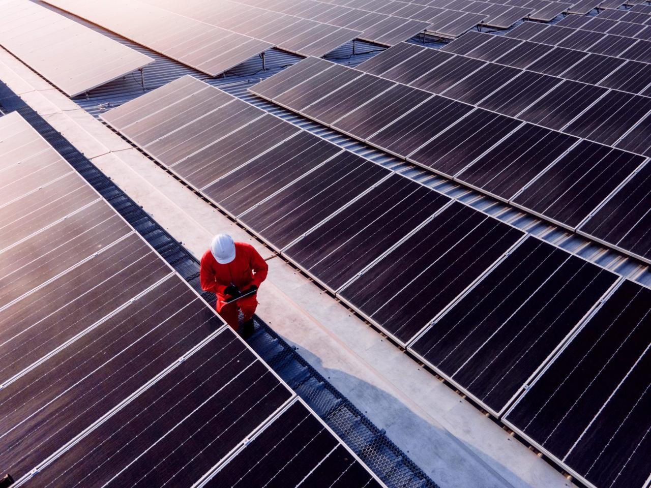 Worker in a hard hat next to solar panels