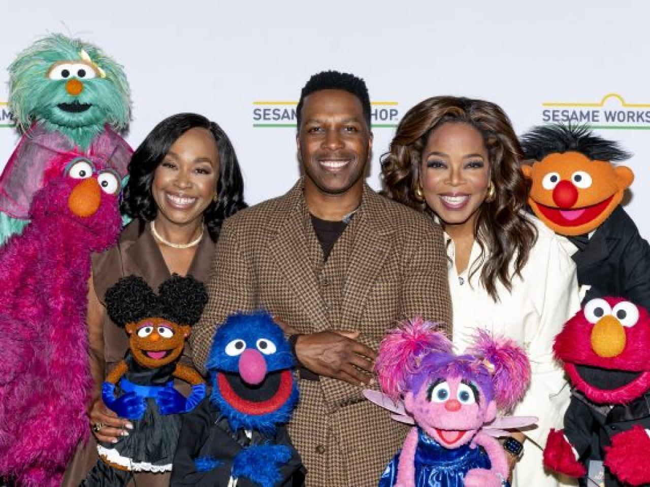 Three people and muppets posed together.