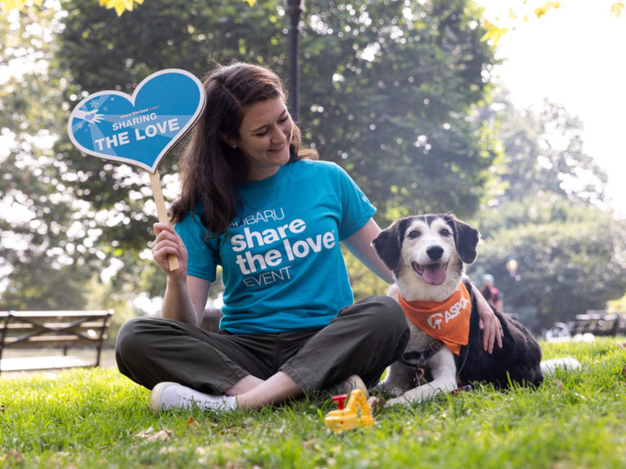 Person wearing "Subaru share the love event" shirt sitting next to a dog