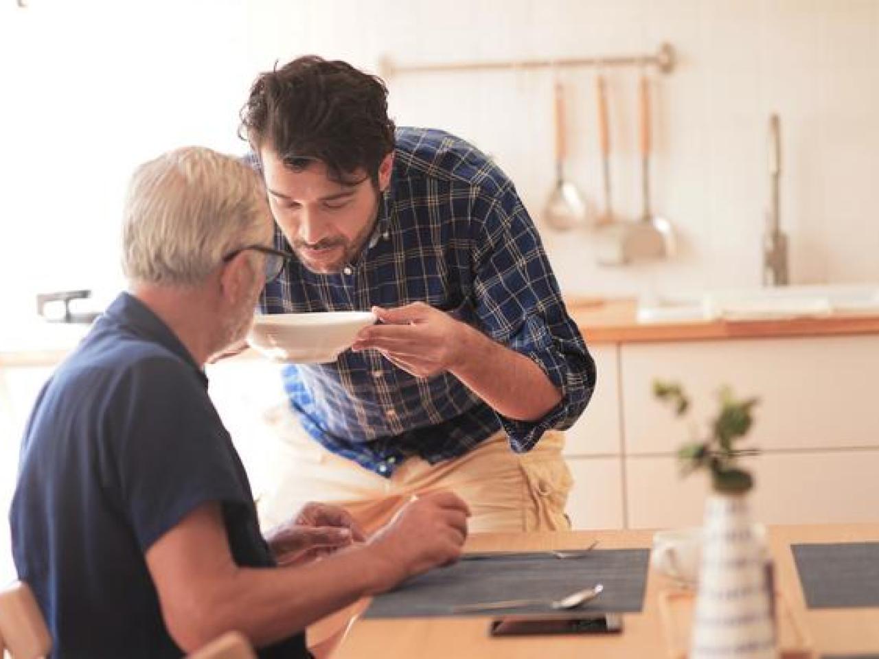person helping another drink soup