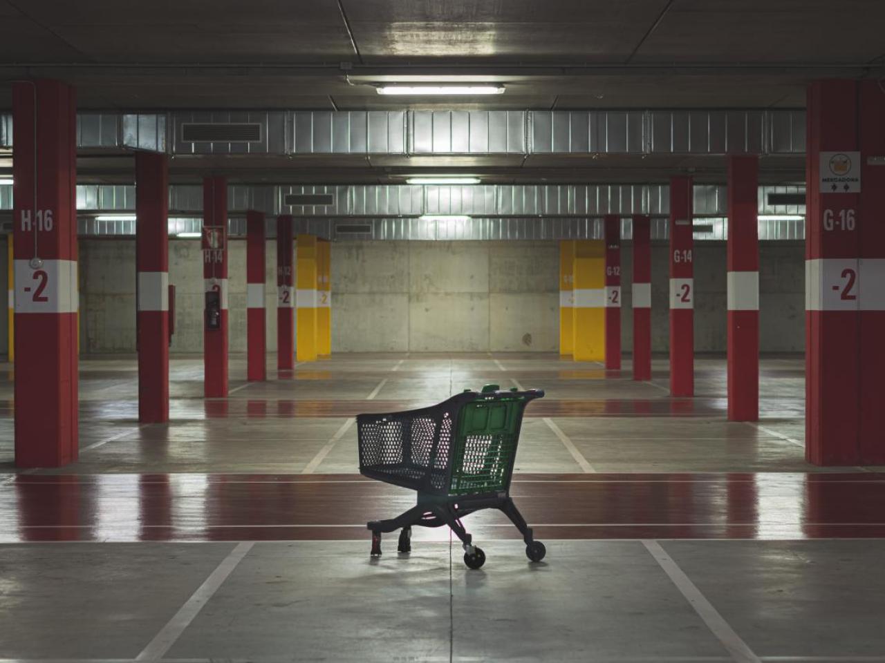 An empty parking garage and a lone grocery cart.