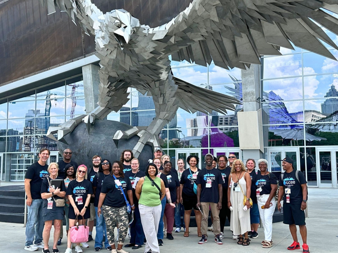 A smiling group posing in front of an eagle sculpture