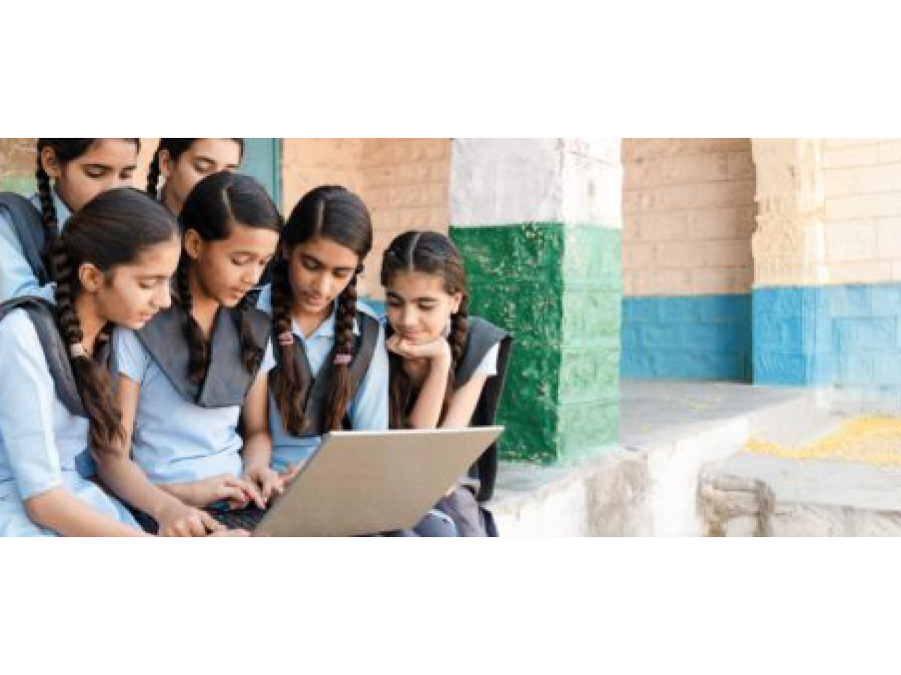 A group of young students gathered around a laptop