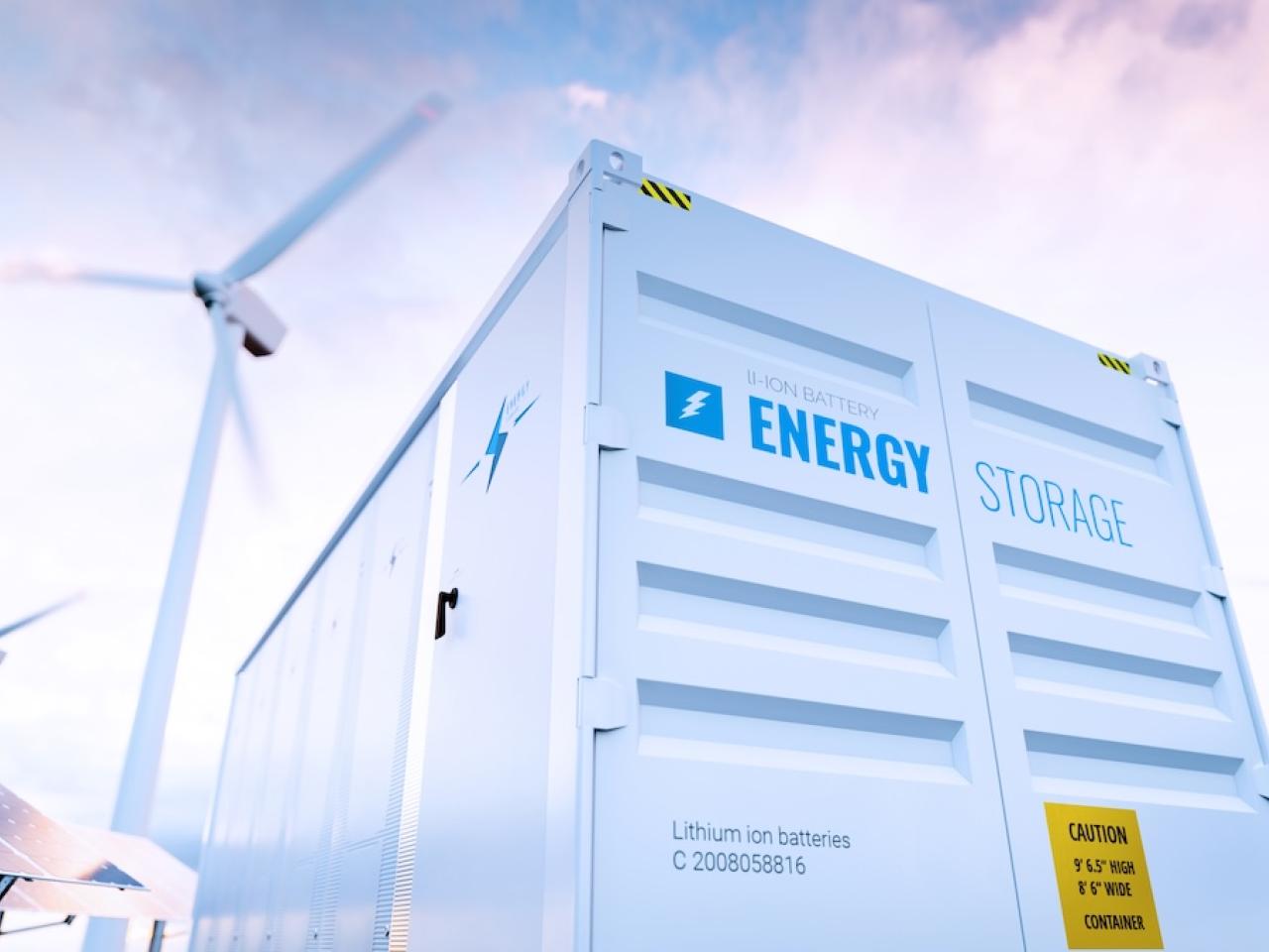 Energy storage container with windmills and solar panels in background