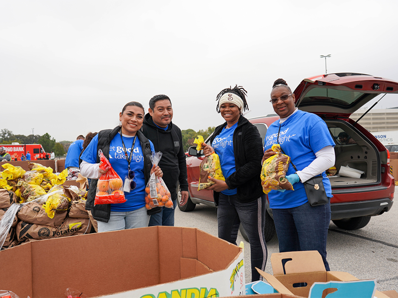 Volunteers packing bags of food into the back of a vehicle.