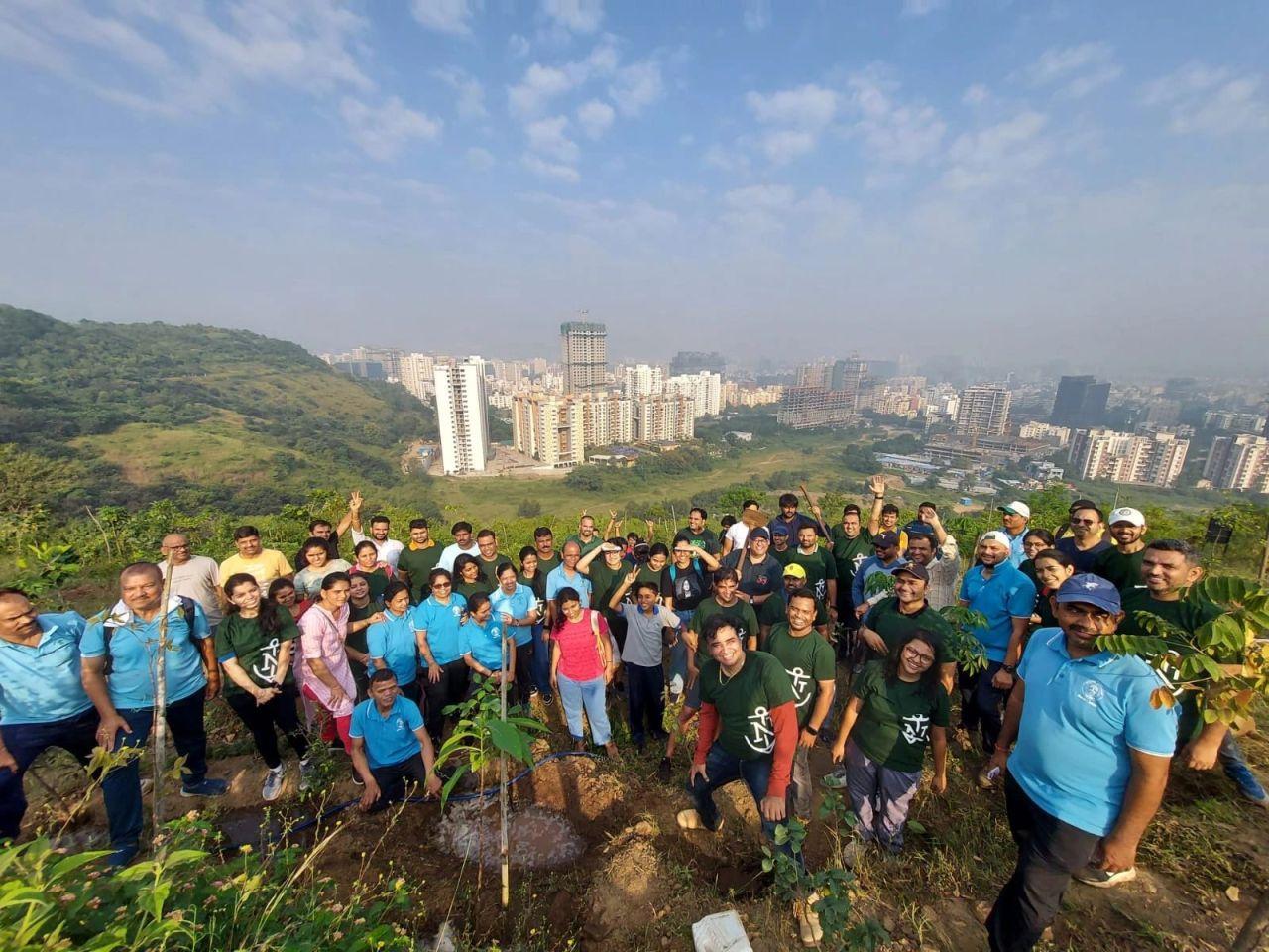 A large group of volunteers posed on a hillside, a city landscape behind them.