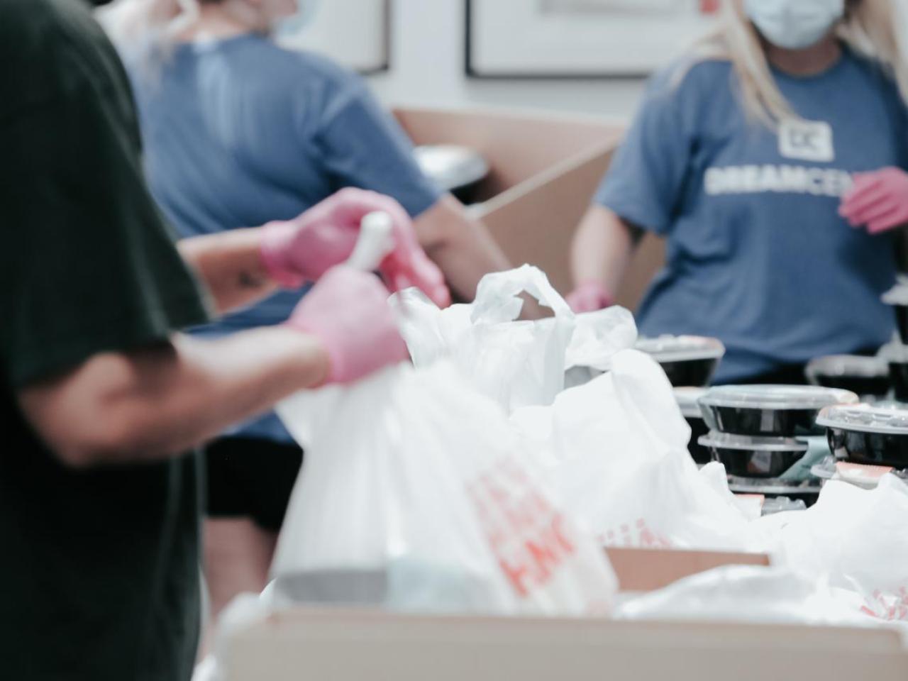 Volunteers packing food item in boxes.