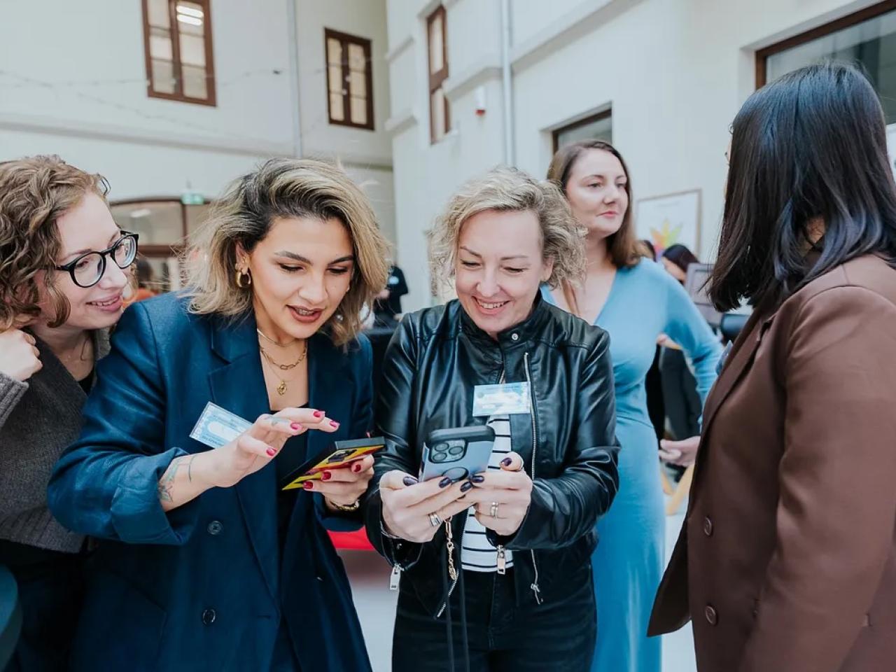Women dressed in business attire eagerly looking at phones