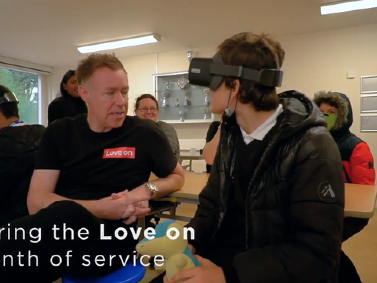 Person in VR headset facing a man in a Lenovo t-shirt