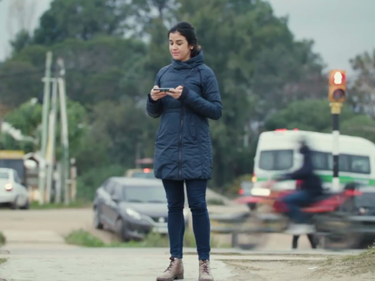 A woman in a blue coat standing outside holding a cell phone