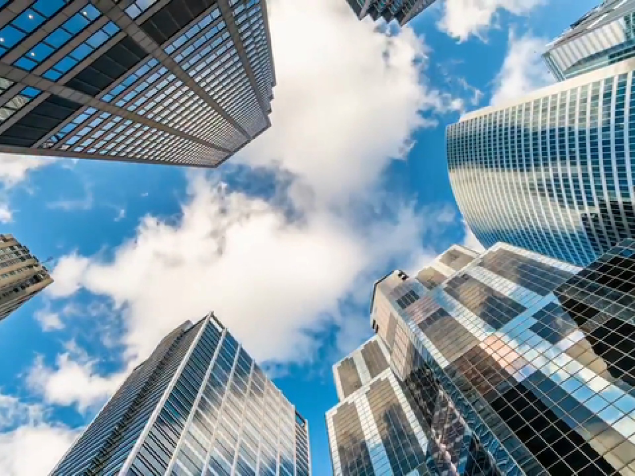 Photo of a blue sky looking up through a group of skyscrapers.