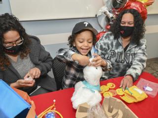 Child seated with two adults receives an Aflac My Special Duck.