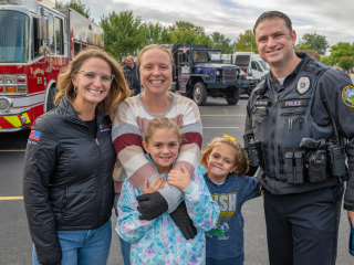 A family and police officer, a fire truck in the background