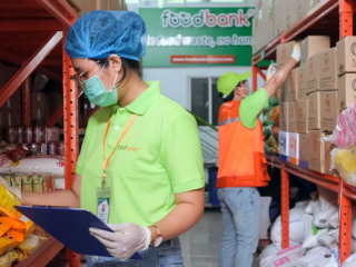 two workers in ppe collecting food items from a warehouse