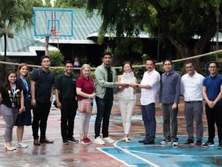 a group of people on a basketball court, three holding an award