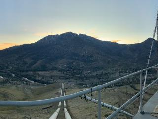 Panoramic view of the valley from a tall building with a safety rail. A road leading down the hill.